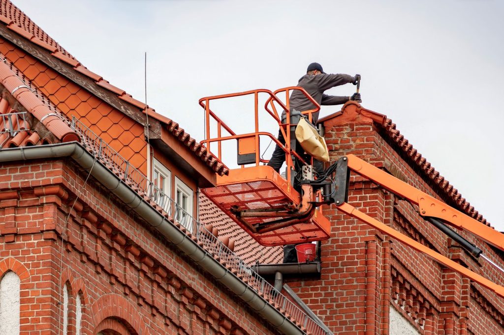 Takläggare vid arbete med taktäckning på ett bostadshus.